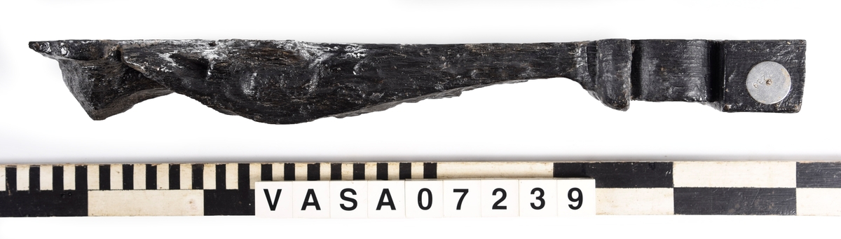 Liten skulpterad pilaster, utformad som en karyatid eller möjligen en putto. Figuren har långt hår och ett knubbigt ansikte, omgivet av en bred krage. Det nedåt avsmalnande pilasterskaftet är dekorerat med akantusblad. Nedtill avslutas pilastern av en rikt profilerad och dekorerad sockel. Skulpturens baksida är slät.
Skulpturen är sliten, främst den övre delen.

Text in English: A small carved pilaster, with a caryatid or probably a putto. The figure has a chubby face, long hair and a broad collar. The lower part of the pilaster is decorated with acanthus leaves. The caryatid stands on a richly profiled and decorated socle. The back of the sculpture is smooth.
The sculpture is worn.