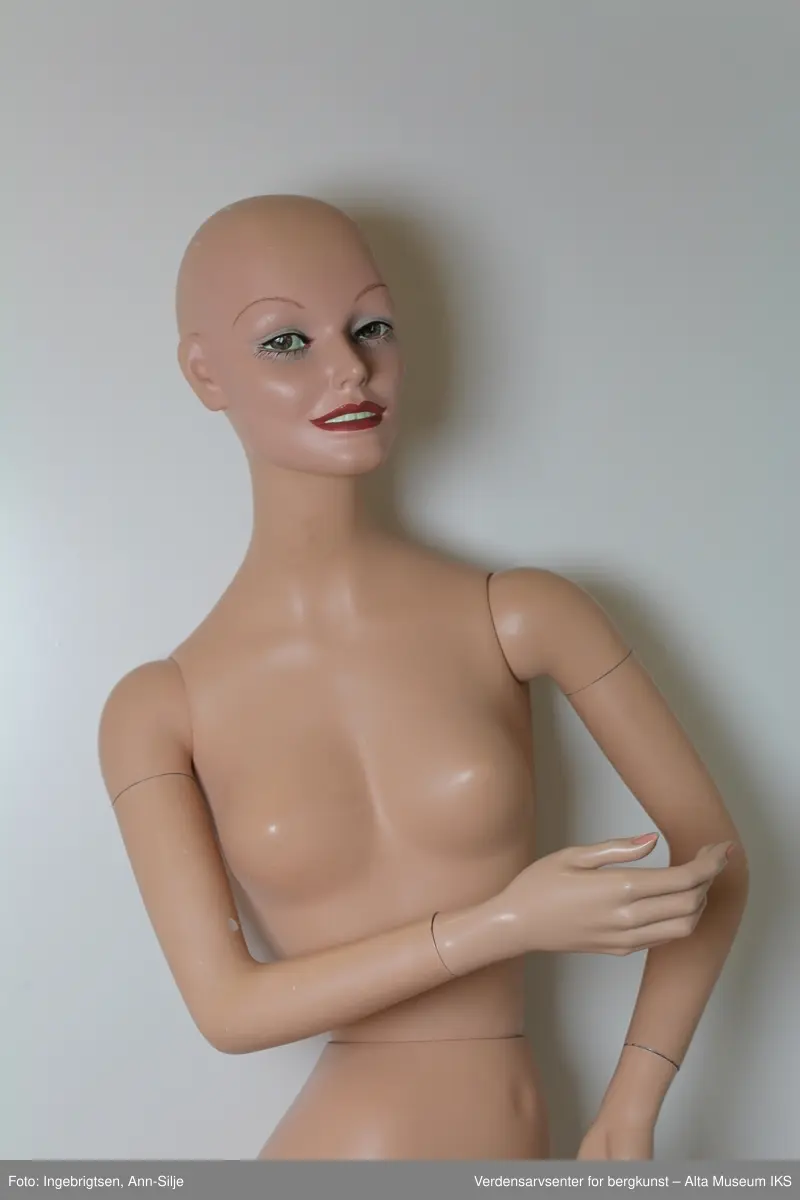 To utstillingsdukker for dame- og herreklær. Herredukken er iført brun dress, hvit skjorte, rødt slips og brune sko.