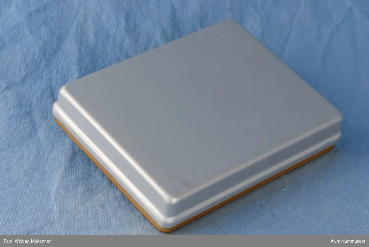 Teknikk: Brettet (farvet) er presset i ett trekk i mellomstore presser, se bilde nr.2 til venstre og nr. 19 til høyre. Brettet er renskåret, gradet, eloksert og farvet.
Lokket er presset i to trekk. Det er renskåret, gradet og natureloksert. 
Form: Lav, firkantet form
