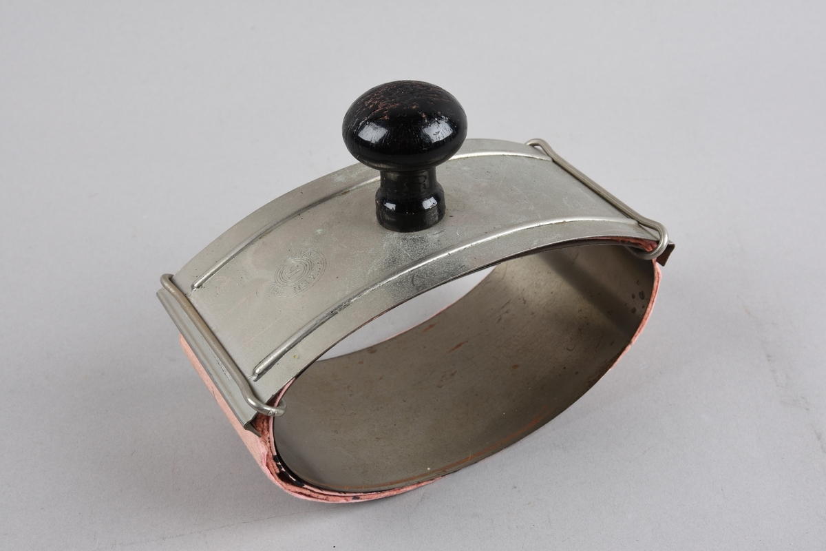 Haldar for trekkpapir. Eit flatt metallstykke bøygd til oval form og føyd saman med overlapping. Trekkpapir rundt denne delen. På toppen av ovalen eit anna flatt metallstykke, rektangelforma med to klemmer som og går over den ovale delen. Papiret vert klemt fast mellom dette stykket og ovalen. På toppen av det svakt bua rektangulære stykket er feste ein  treknott til å halde i