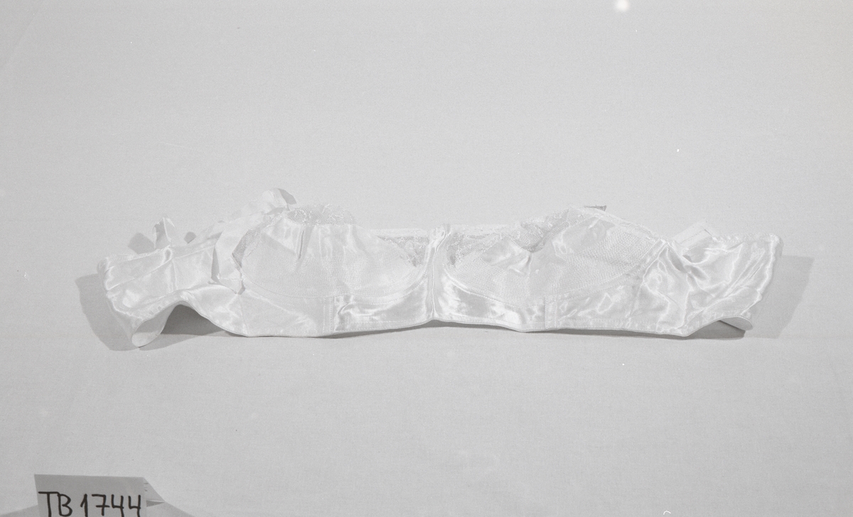 BH med regulerbare stropper uten elastikk. Forsterket i underkant av cup med blonder over. En hekte til lukning bak.