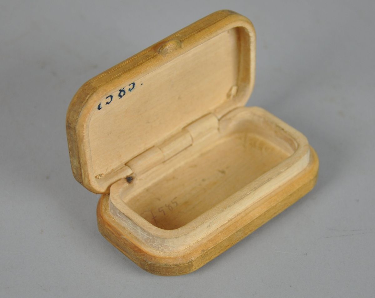 Rektangulær eske av tre, med avrundede kanter. På lokk og underside er det innrisset sirkulære streker. 

Dypere hakk enkelte steder i innrissingen kan tyde på at den dekorative treskjæringen er uferdig.