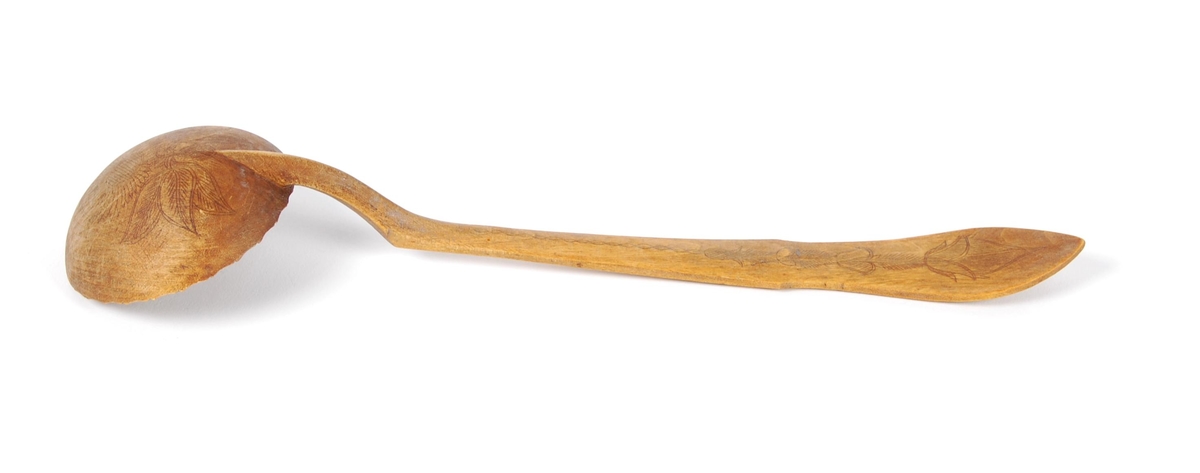 Skje av bjørk. Skjeblad tilnærmet sirkelformet, tungekant, kort nebb, kolrosingdekor på over- og underside hovedsakelig med blad- og blomstermotiver Buet hals. skaftet svakt bøyd nær enden, kolrosingdekor på over og underside med blad og blomstermotiver.