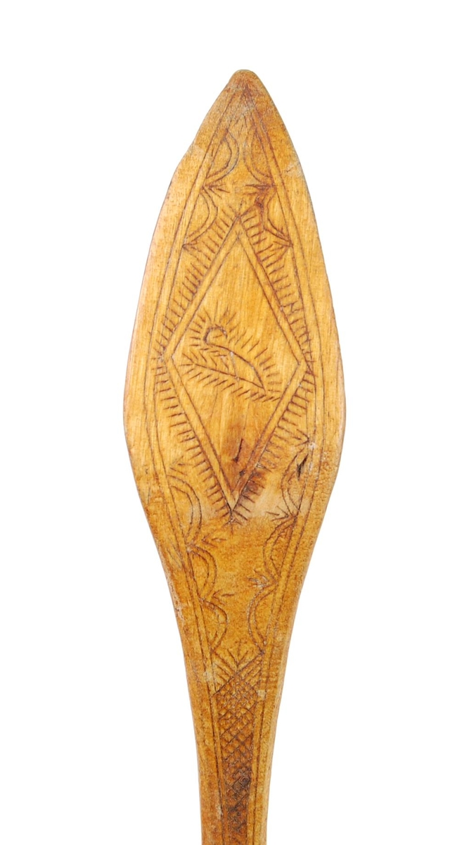 Skje av bjørk. Dypt skjeblad med nebb, i bunnen kolrosingdekor i form av bl.a. en stjerne, undersiden med kolrosingdekor i form av blader og blomster. Buet skaft med kolrosingdekor på over- og undersiden, undersiden har innskrift