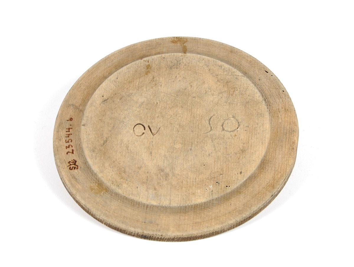 Tallerkner av dreid bøk. Sirkelrund med svak opphøyet ytterkant. Buemerke på ene siden.