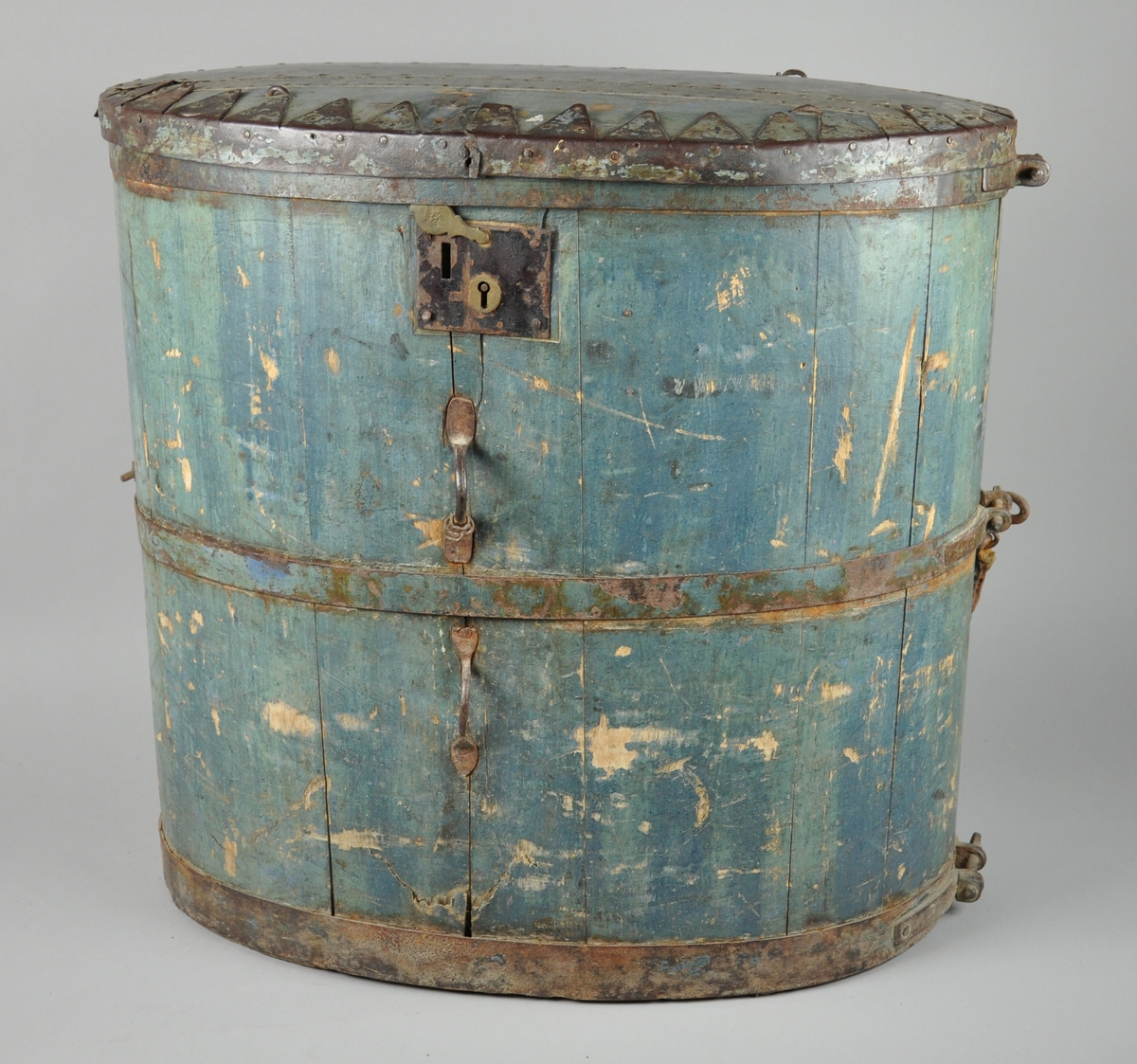 Kløvbomme lagget med 15 staver. Treverket og deler av metallet er blåmalt, lokket er i stor grad armert med metall. To håndtak av lær på baksiden. På baksiden er det også en stoffreim, festet i metallhåndtak på sidene. På framsiden sitter det en lås med innskriften 'secure'

På baksiden har mye av malingen flasset av.
På nedre framside er det en sprekk i treverket.