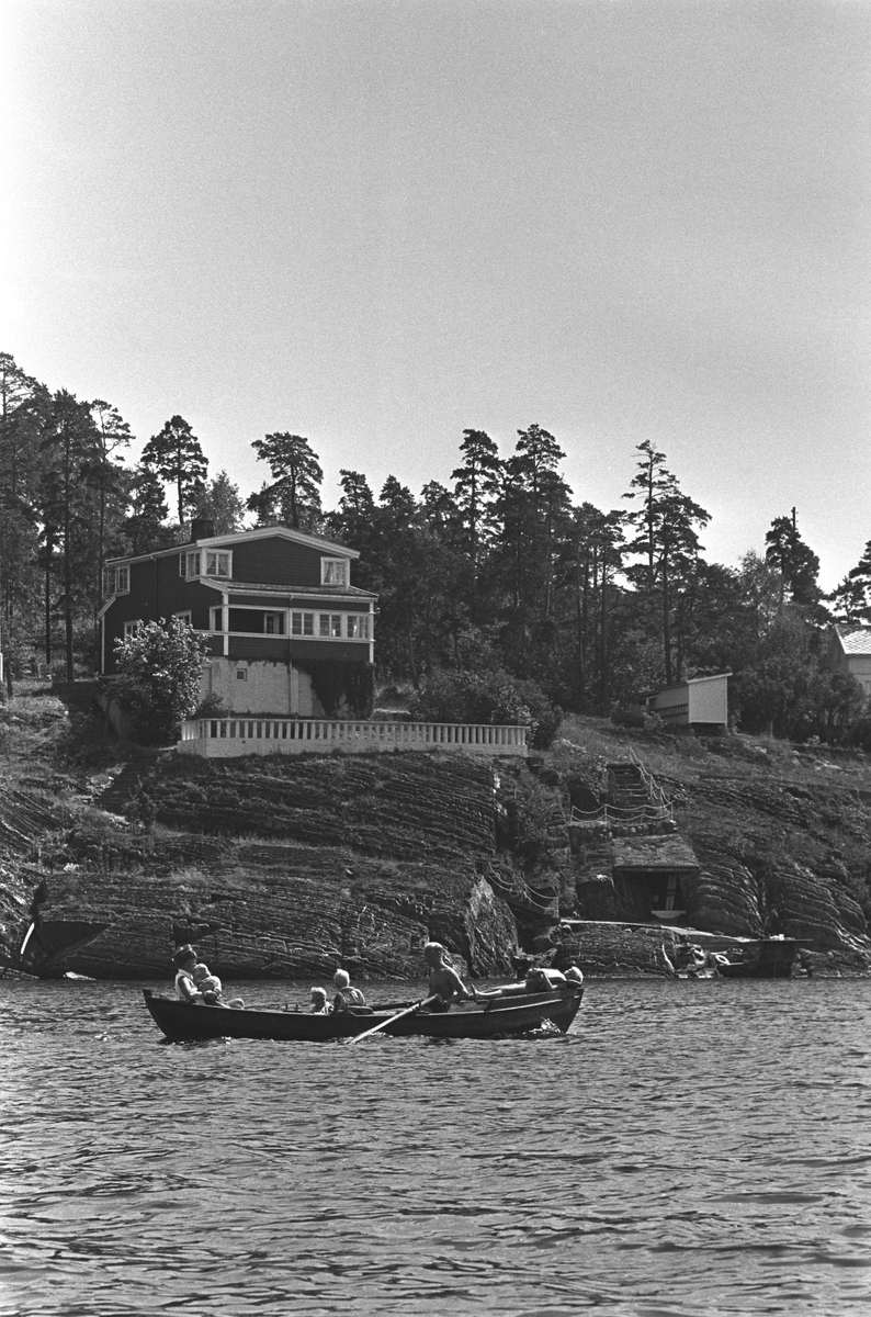 Erik Damman, reklamekonsulent fra Oslo, ferierer i båt med familien i Oslofjorden. De skal ro 10 - 12 mil i løpet av 8 - 10 dager, og går i land på små holmer som fjorden har mange av.  Fra venstre i båten Ragnhild Damman og minstemann Jaran (1,5). I midten Are (8), Brede (5). Erik Damman og Rein (10) til høyre.