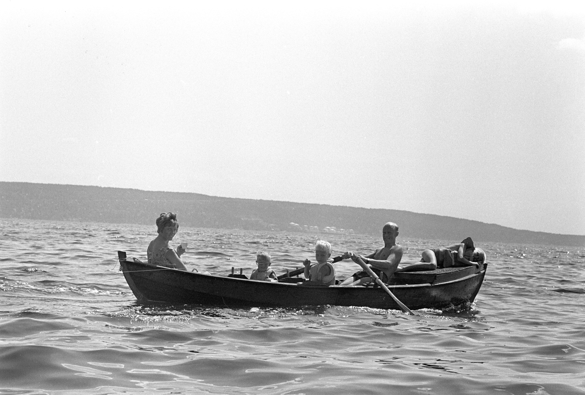 Erik Damman, reklamekonsulent fra Oslo, ferierer i båt med familien i Oslofjorden. De skal ro 10 - 12 mil i løpet av 8 - 10 dager, og går i land på små holmer som fjorden har mange av. Her sitter Erik Damman ved årene. Ragnhild Damman til venstre. Midt i båten Are (8), Brede (5) og Rein (10) helt forut.