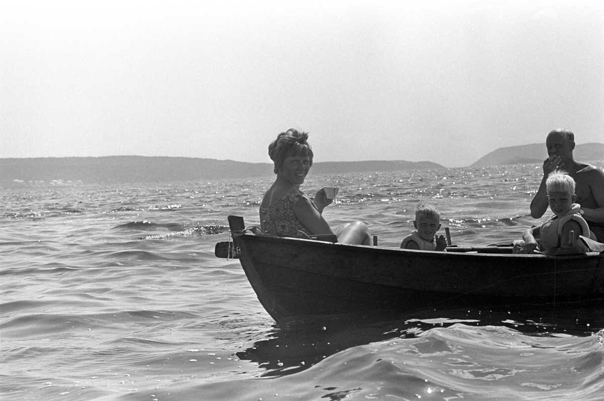 Erik Damman, reklamekonsulent fra Oslo, ferierer i båt med familien i Oslofjorden. De skal ro 10 - 12 mil i løpet av 8 - 10 dager, og går i land på små holmer som fjorden har mange av. Her sitter Erik Damman ved årene. Ragnhild Dammen til venstre. Midt i båten sitter Are (8) og Brede (5).