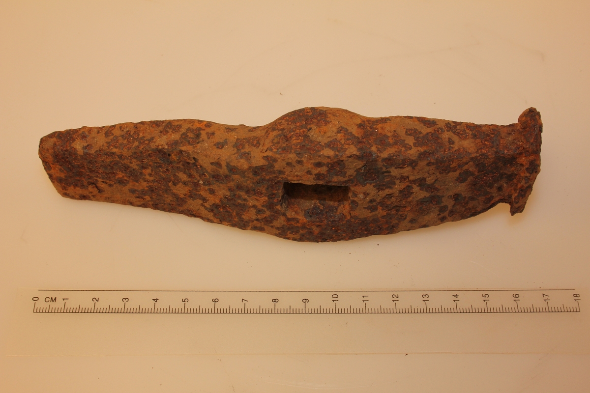 Rektangulær form. Jamt smalande i eine enden. Andre enden er butt, brukt til å slå mot harde gjenstandar. Kvadratisk hol på midten.