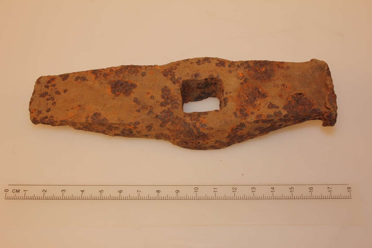 Rektangulær form. Jamt smalande i eine enden. Andre enden er butt, brukt til å slå mot harde gjenstandar. Kvadratisk hol på midten.