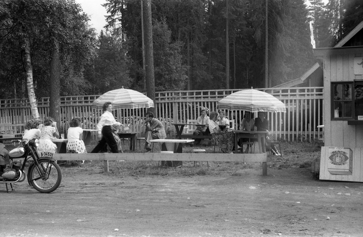 Bilde trolig tatt ved en kafe et sted langs gamle rv. 50 mellom Minnesund og Oslo juni 1953. Ingen av personene er identifisert.