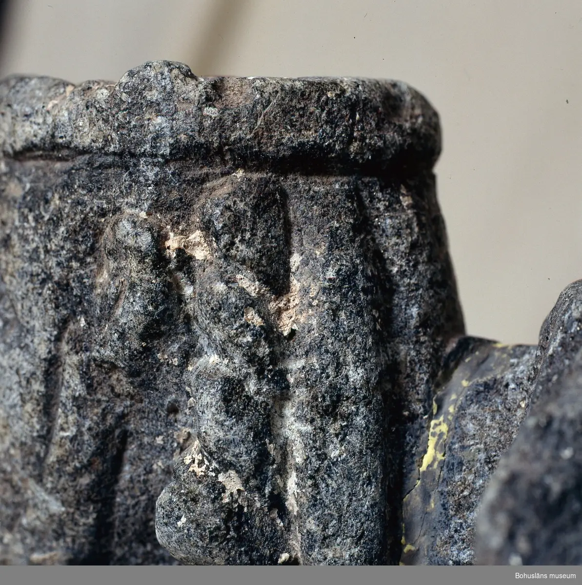 Stenskulptur av täljsten från Svarteborgs kyrka. Den helige Olof sittande i tronstol med högt ryggstöd. Han bär livbälte och mantel, en murkrona på huvudet, möjligen ett relikvarium i höger hand och håller vänster hand om skägget. Skulpturen är starkt eroderad.

Ur handskrivna katalogen 1957-1958: Olav d. helige, täljsten, Svarteborg. M: H. 41, största Br. 32,5 cm; krona och mantel, i höger hand spiran, vänster griper om skägget; sittande på en tronstol m. armstöd och högt ryggstöd, på alla håll smalnar stolen av uppåt. Starkt sliten.

Ur Katalog 1. Uddevalla Museihistoriska samlingar, svenska avdelningen. A. Yngre föremål. Upprättad av Knut Adrian Andersson 1916:                                                                                                                              No 34. Bild i täljsten av Olov den Helige. Yngre medeltiden, räknad till 1550. Förvarats i Svarteborgs kyrka under namnet "Kung Rane". Skänkt av församlingen år 1860-70-tal till Uddevalla museum. Förvaras ovanpå Medeltidsskåpet i sydvästra rummet.

Presenterad i  Uddevalla Museums tryckta katalog 1869 under rubriken 
F] Saker från yngre Medeltiden, räknad till 1550.
N:o 1. Bilder af S:t Olof i sten från Svarteborgs kyrka.

1861-1870 1 Arkeologiska och Etnografiska samlingarna U-a Museum D4A 1
Ur Gåvobok1864:
Svarteborgs församling:
Kristusbild af träd samt fragmenter af en Granit- [överstruket] Täljstensbild, enligt sägen föreställande Kung Rane, hvilka begge setat [överstruket] [oläsligt tillägg] i Svarteborgs kyrka. 
Tillagd kommentar av intendent Knut Adrian Andersson; Olof d. Helige troligen.

Se foton på föremålet i Uddevalla museums kyrkliga utställning 1920, UMFA54467:0089.
Tillstånd, se Vårdblankett.