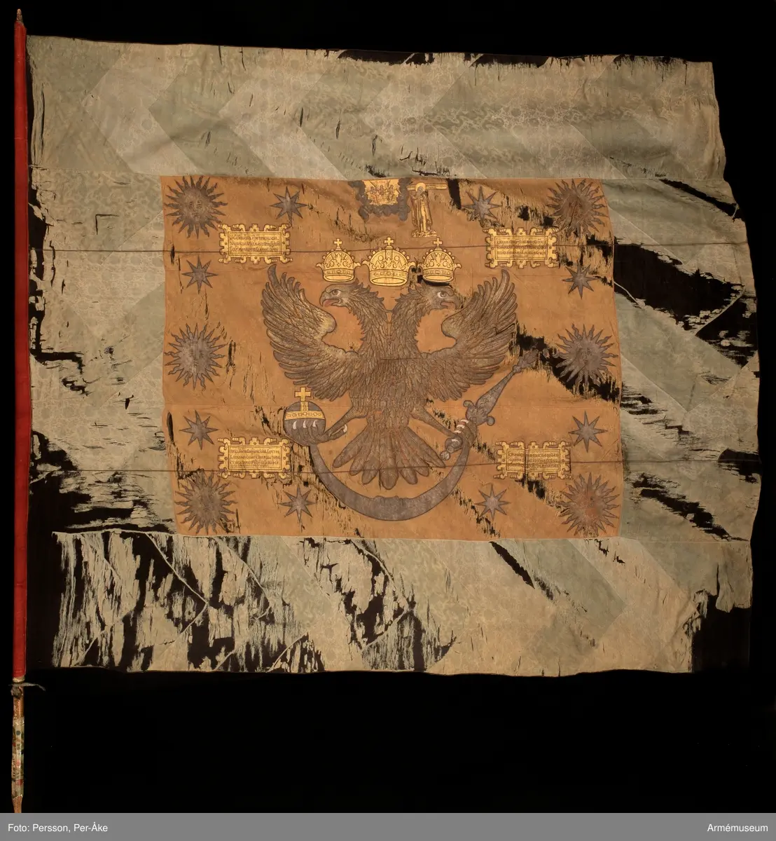 Fotfolksfana från den ryska staden Pskov.

Fanan har ett mittfält av ursprungligen röd kinesisk sidendamast, inom en bred blå och grön sicksackmönstrad bård. Den är dekorerad med intarsiabroderi och målade detaljer. Strumpan är av ylle.
På båda sidor av fanduken ses den tvåhövdade ryska örnen krönt med tre kronor vilka representerar de tre tsarrikena Kazan, Astrachan och Sibirien. Ovanför örnen syns den gammaltestamentliga framställningen av treenigheten samt bredvid helgonet Sergej av Radonesj. Örnen omgärdas på båda sidorna av sex solar och åtta stjärnor, samt 5 kartuscher med svart text på guldbotten.
Den ryska texten i kartuscherna lyder i översättning:
”Den 2 mars år 7201 (1693) under den tid, då regeringen fördes av deras högheter och storregenter, med Guds nåde tsarer och storfurstar Ivan och Peter Alexejevitj, hela, stora, lilla och vita Rysslands självhärskare, och under den tid, då överokolnitjen, vojevoden och guvernören över Nizjegorod Peter Matvejevitj Apraksin med närmaste män vistades i riket Pskov, lät stolniken Ivan Michailovitj Kokosjkin överste för Pskovs första streltserregemente, utföra denna fana. ”

Den kinesiska damasten är mönsterad med krysantemum, lotus, trädpion, granatäpple, Buddas-hand-citron samt olika värdeföremål.