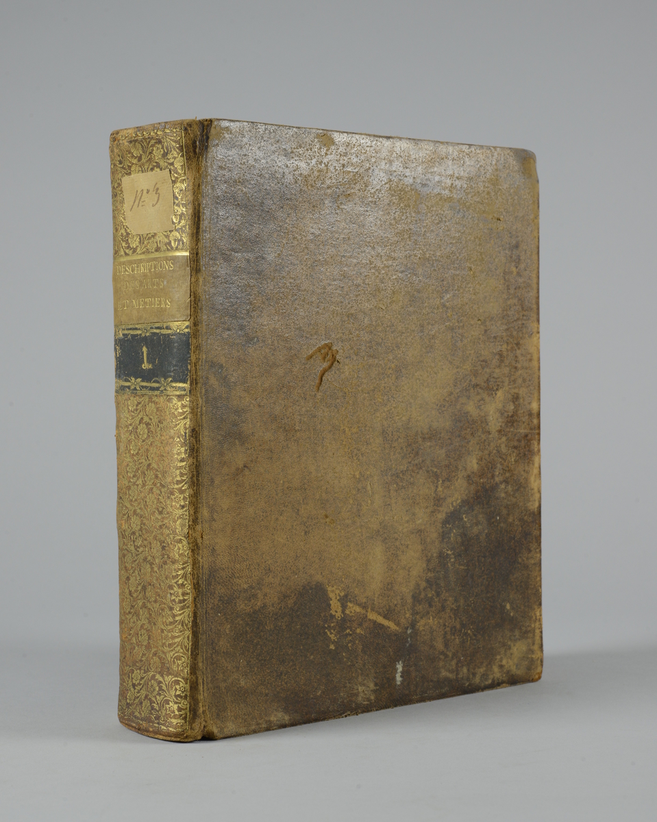 Bok, "Descriptions des arts et metiers" av J. E.  Bertrand, utgiven 1771, del 1. 
Helfranskt band med rygg med guldpräglad dekor, titelfält med blindpressad titel och ett mörkare fält med volymens nummer. Påklistrad pappersetikett med nummerbeteckning med bläck. Med rött snitt. Marmorerat papper klistrat på pärmarnas insidor.
Planscher i koppartryck.