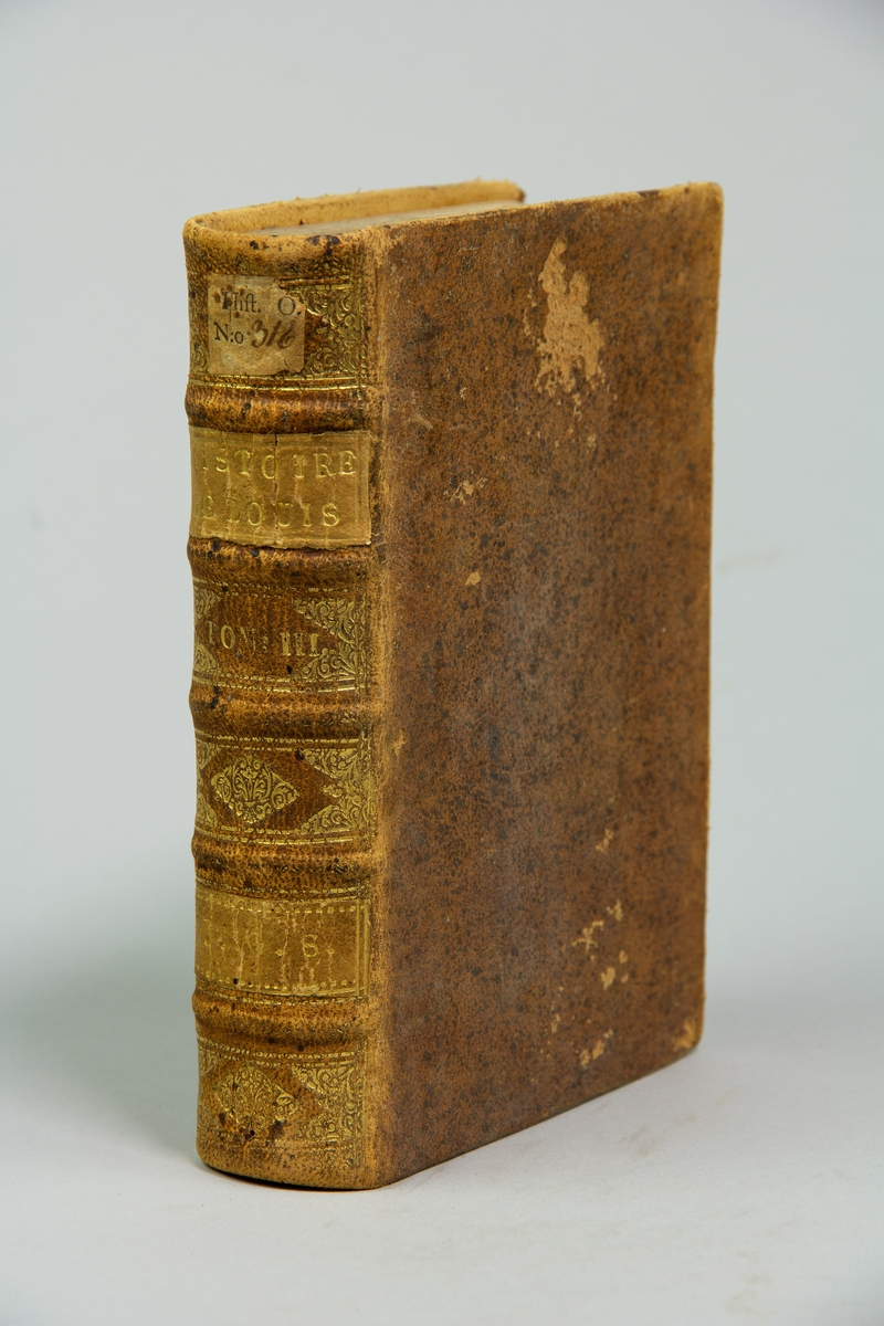 Bok, helfranskt band "Histoire de France sous le regne de Louis XIV",del III, skriven av de Larrey, tryckt i Rotterdam hos Michel Bohm & Compagnie, 1721.
Skinnband med blindpressad och guldornerad rygg i fem upphöjda bind, titelfält med blindpressad titel , fält med volymens nummer och ett fält med ägarens initialer samt påklistrad pappersetikett. Med stänkt snitt.