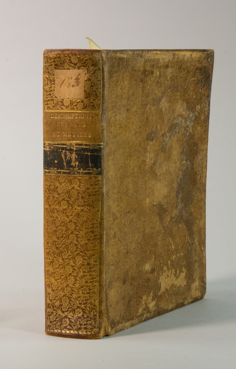 Bok, helfranskt band "Descriptions des arts et métiers" ny upplaga, vol. VI, med planscher i kopparstick, utgiven av J.E. Bertrand och tryckt i Neuchatel 1776.  
Skinnband med blindpressad och guldornerad rygg, titelfält med blindpressad titel och ett mörkare fält med volymens nummer. Pärmens insida klädd med marmorerat papper. Med rött snitt.
Påklistrad etikett märkt med bläck "No 3."