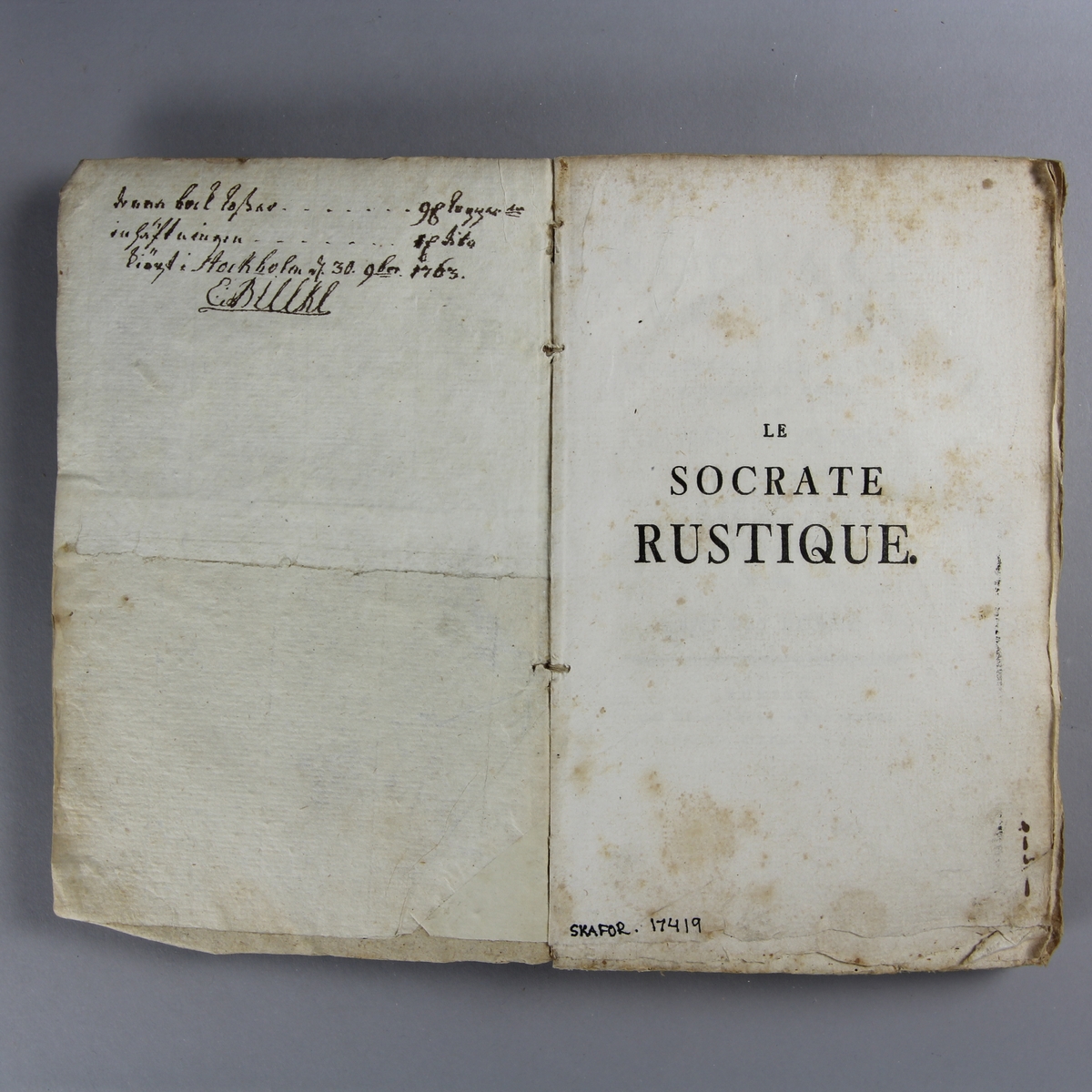 Bok, häftad,"Le Socrate rustique",  tryckt i Zürich 1762.
Pärm av gråblått papper, oskurna snitt. Blekt rygg med pappersetikett med volymens namn och samlingsnummer.