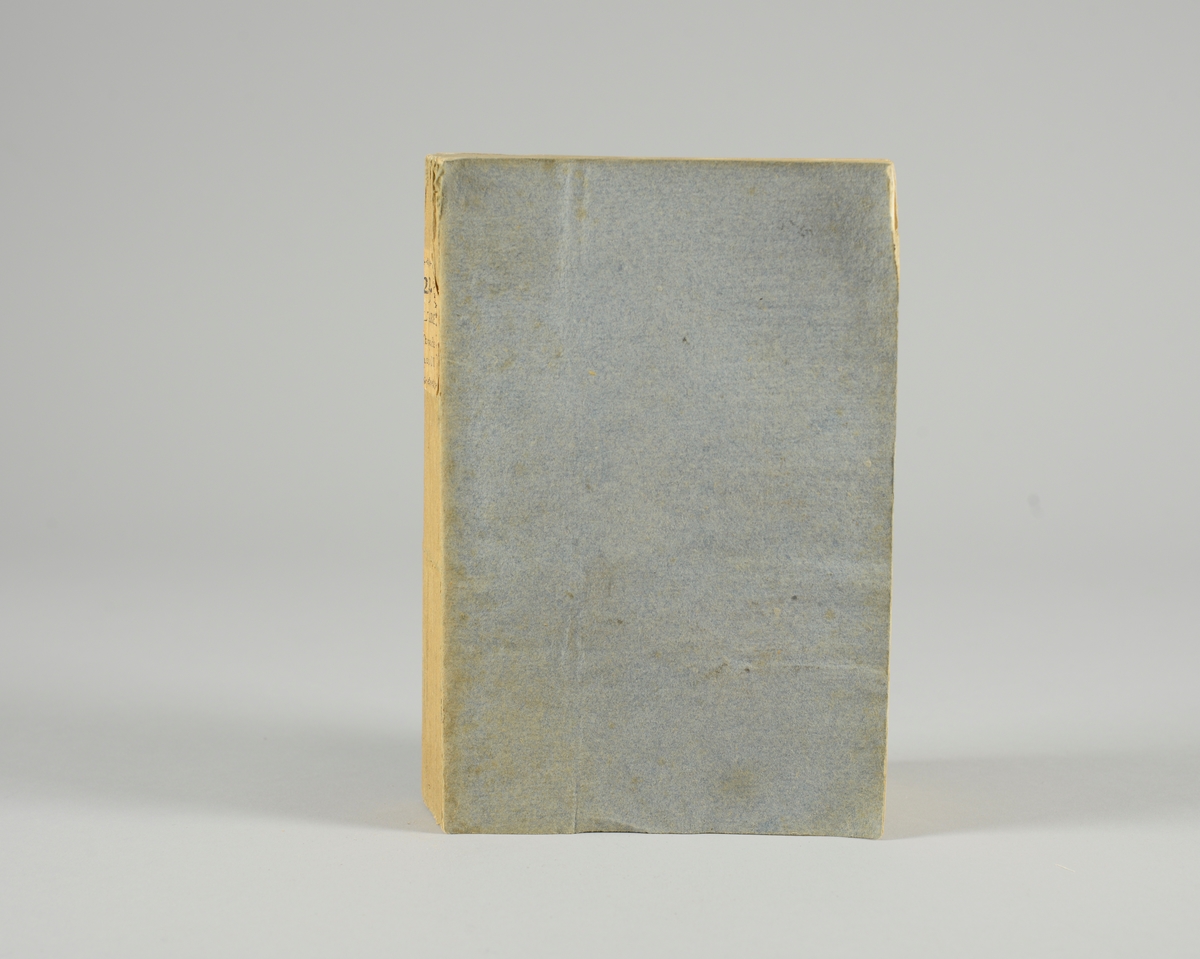 Bok, pappband,"Oeuvres completes de Voltaire", del 23 Histoire de Charles XII, tryckt 1785.
Pärmen klädd med gråblått papper, på pärmens baksida klistrad sida ur annan bok. Med skurna snitt. På ryggen klistrad pappersetikett med tryckt text samt volymens nummer. Ryggen blekt.