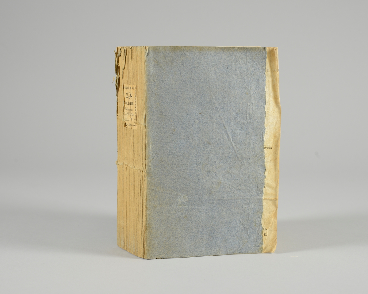 Bok, pappband,"Oeuvres completes de Voltaire", del 29, tryckt 1785.
Pärmen klädd med gråblått papper, skurna snitt. På ryggen klistrad pappersetikett med tryckt text samt volymens nummer. Ryggen blekt.