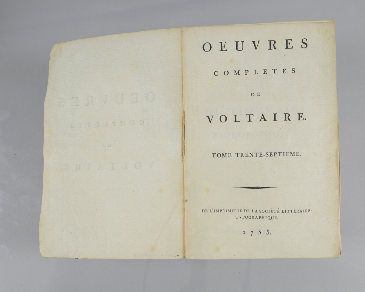 Bok, pappband,"Oeuvres completes de Voltaire", del 37 "Dictionnaire philosophique", tryckt 1785.
Pärmen klädd med gråblått papper, på pärmarnas insidor klistrade sior ur annan bok. Med skurna snitt. På ryggen klistrad pappersetikett med tryckt text samt volymens nummer. Ryggen blekt.