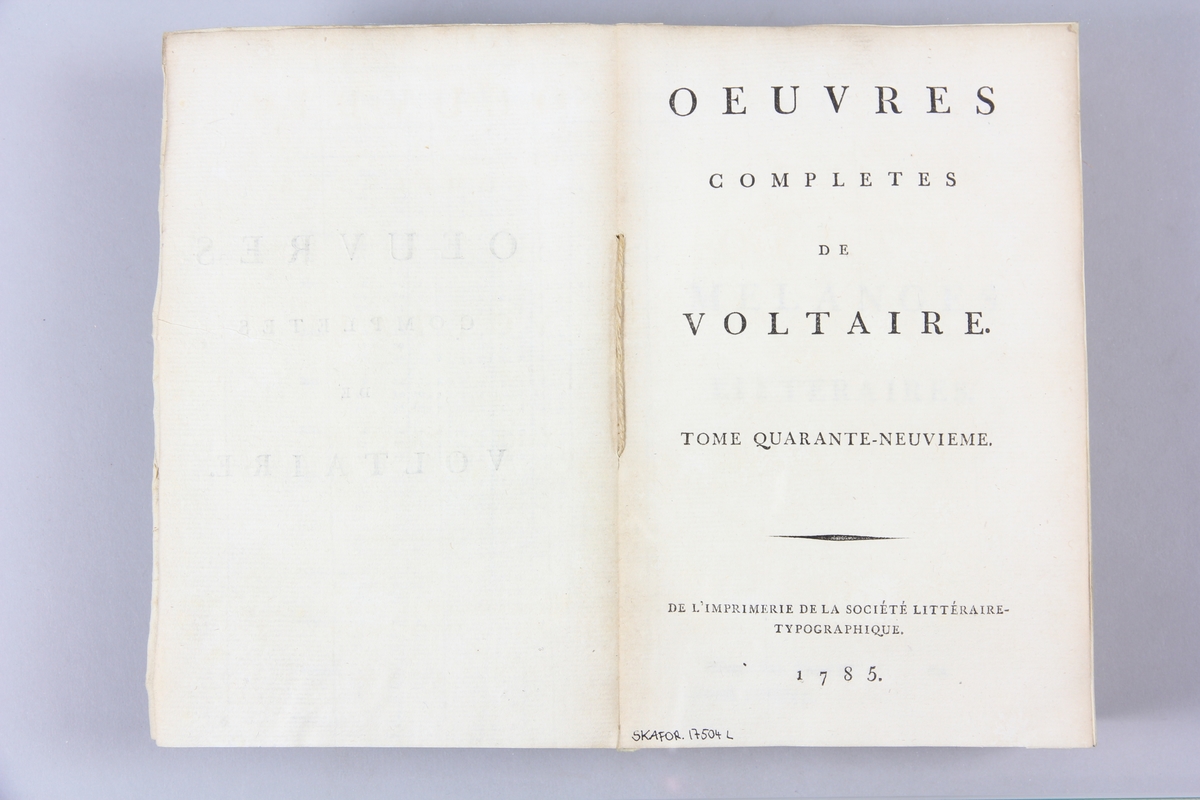 Bok, pappband,"Oeuvres complètes de Voltaire."  del 49, tryckt 1785.
Pärm av gråblått papper, på pärmens insidor klistrade sidor ur annan bok. Med skurna snitt. På ryggen pappersetikett med tryckt text med volymens namn och nummer. Ryggen blekt.