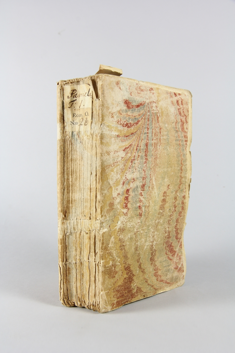 Bok, häftad" Pamela ou la vertu recompensée", del 1, tryckt 1743 i Amsterdam. Pärm av marmorerat papper, oskuret snitt. Blekt rygg med pappersetikett med volymens namn och samlingsnummer.