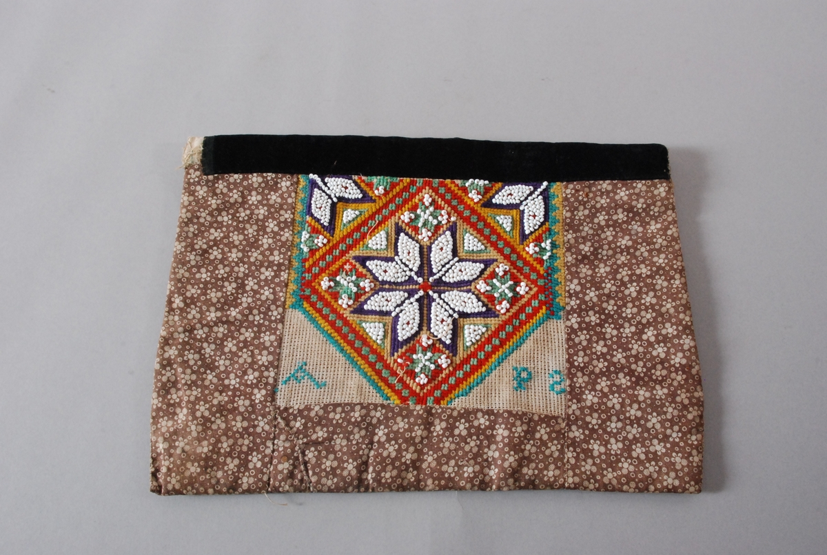 Hovedmotivet er ei åttebladrose i perlebroderi med to 1/4 dels åttebladroser (perlebroderi) oppe i kvart hjøre innenfor ein firkant. Resten av dekoren er broderi med tråd med litt perler inni mellom. Nederst i firkantens venstre hjørne er det brodert en A og nederst i høgre hjørne er det en P og en omvendt S.