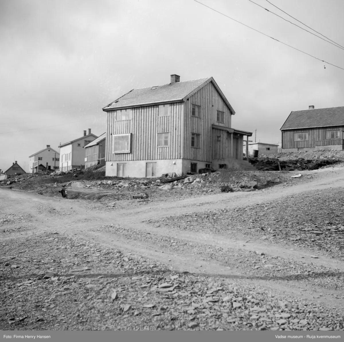 Vadsø, Bildet er tatt mot nordvest i krysset Nyborgveien og Oscarsgate og med Tollbugata ned mot syd. Vi ser flere gjenreisningshus, 
Sarajervi-huset, Nyborgveien 1, tilhørende skomaker Sarajervi midt i bildet.