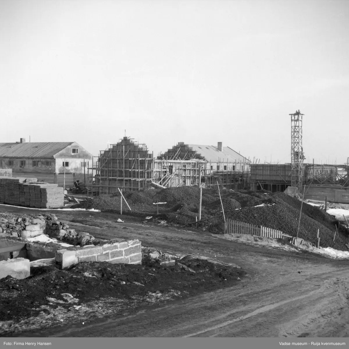 Vadsø sentrum. Gjenreisninga av Sentrum i full gang. Vi ser forretningsbyggene rundt Torget, øst for Tollbugata ; bla  Henry Hansen og Baker Henriksen under oppføring. Deler av bygget til Leif Bjerck i venstre billedkant