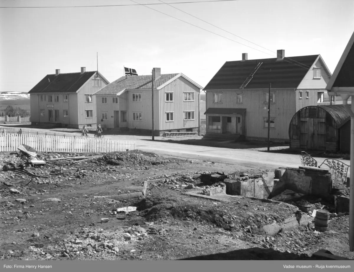 Vadsø mai 1951. I Oscarsgata, bildet er tatt mot sørøst. Tre gjenreisningsbygg, en Nissenbrakke. Ruin i forgrunnen. Kirkegården helt til venstre i bildet. Huset lengst til venstre var administrasjonsbygg for Finnmark fylkes elektrisitetsforsyning (etablert 1946, fra 1975 Finnmark kraftforsyning).
Kilde: Finnmark fylkeskommunes historie / Øystein Bottolfsen. 1990. S.388.