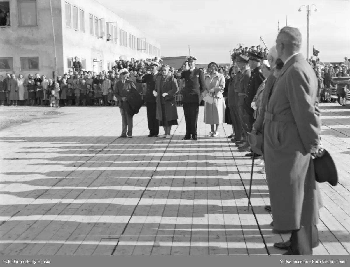 Vadsø. Kongebesøk i Vadsø 1950. Kongen og kronprinsfamilien blir tatt imot på kaia, fra v. prins Harald, kronprins Olav, kronprinsesse Märtha, kong Haakon, prinsesse Astrid. Bildet er tatt mot sør, havnebygget tl venstre.
Kong Haakon og kronprinsfamilien besøkte Vadsø 25.-26.7.1950 i forbindelse med en større rundreise i Nord-Norge sommeren 1950. Under besøket sto "biltur gjennom byen" og "besøk på sykehuset" på programmet. Kilde: Det kongelige hoff, arkivet