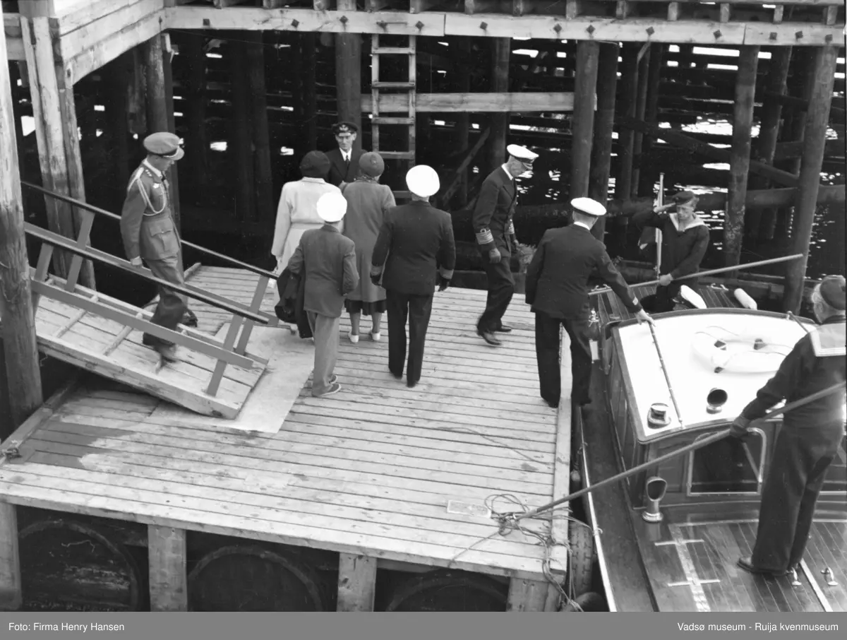 Vadsø. Kongebesøk i Vadsø 1950. Kong Haakon og resten av kongefølget på vei fra flytekaia over i sjaluppen. 
Kong Haakon og kronprinsfamilien besøkte Vadsø 25.-26.7.1950 i forbindelse med en større rundreise i Nord-Norge sommeren 1950. Under besøket sto "biltur gjennom byen" og "besøk på sykehuset" på programmet.            
Kilde: Det kongelige hoff, Arkivet