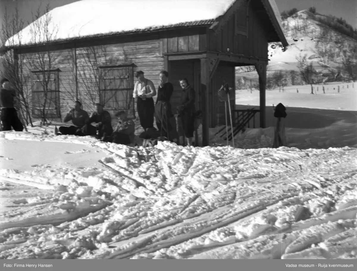 Vinikka. Vinterlandskap. Skiløpere raster foran en hytte.
