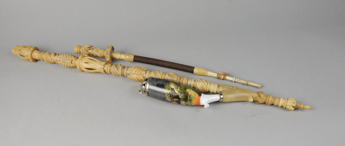 Langpipe i tre deler: Piperør, pipehode og munnstykke. Pipehodet av porselen  er påmalt et skogmotiv med en elg, og harr lokk av sølv. Piperøret og munnstykket er av utskåret alabast. Det midtertste partiet på munnstykket er bøyelig.