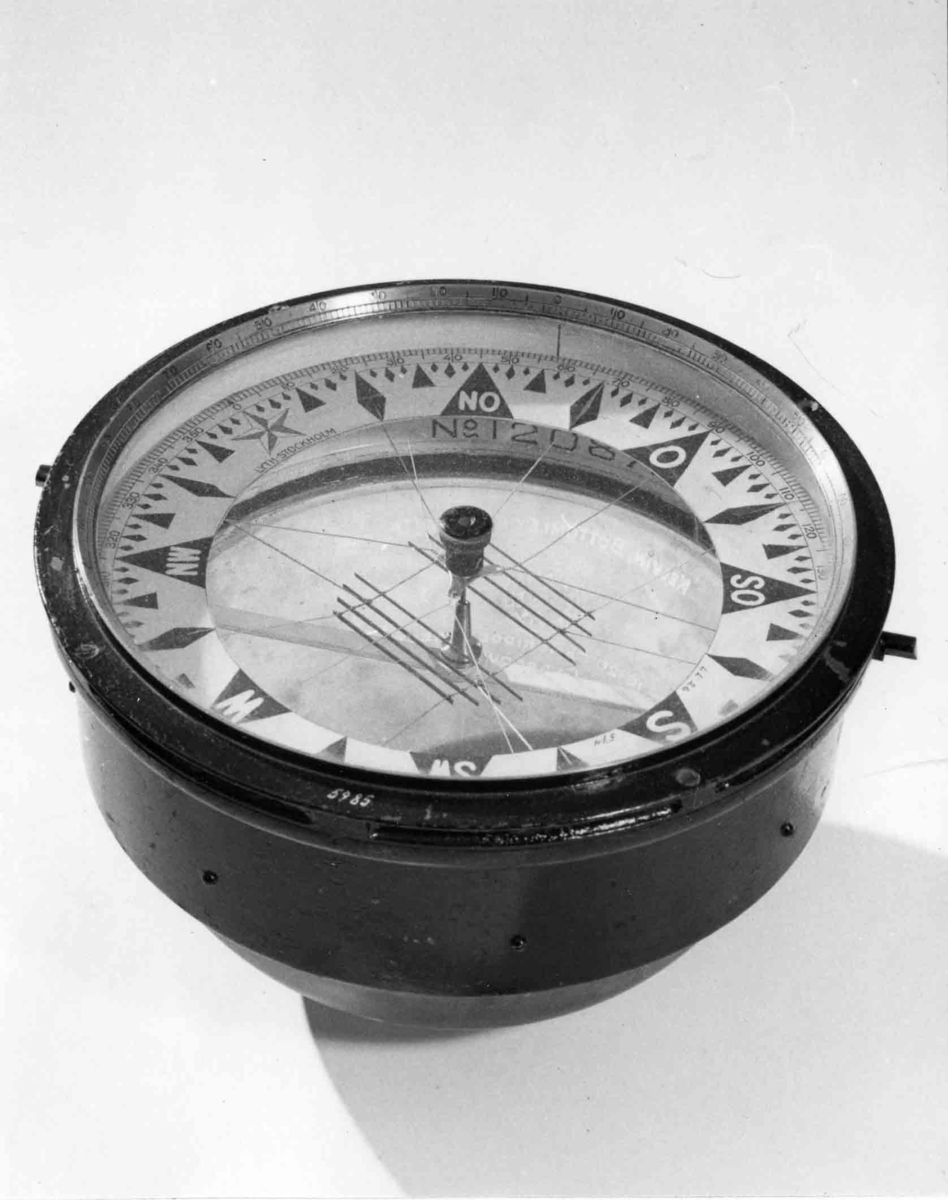 Luftkompass. Cylindrisk med graderad överkant. skål, cylindrisk del av svartmålad mässing, undre sfäriska delen av tjockt glas fylld med glycerin. Skiva med ringformad ros i grader (360) och streck samt nålsystem (8 st.) rödmålat. Rosen märkt: 'Lyth, Stockholm”. Skålen invändigt märkt: 'N:o 12087 
Glasets utsida märkt:  "Kelvin,Bottomley & Baird LTl. 16-20 Cambridges street Glasgow Patent N:o 22032 oz.” 
Har tillhört övningsskeppet "af Chapman”.