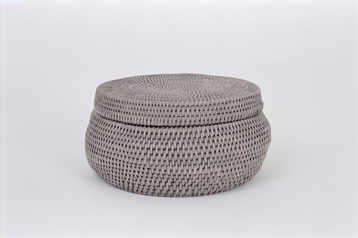 Korg bunden av kluvna rottågor över vidjor med löst lock. Rund bukig form med platt botten och platt lock.