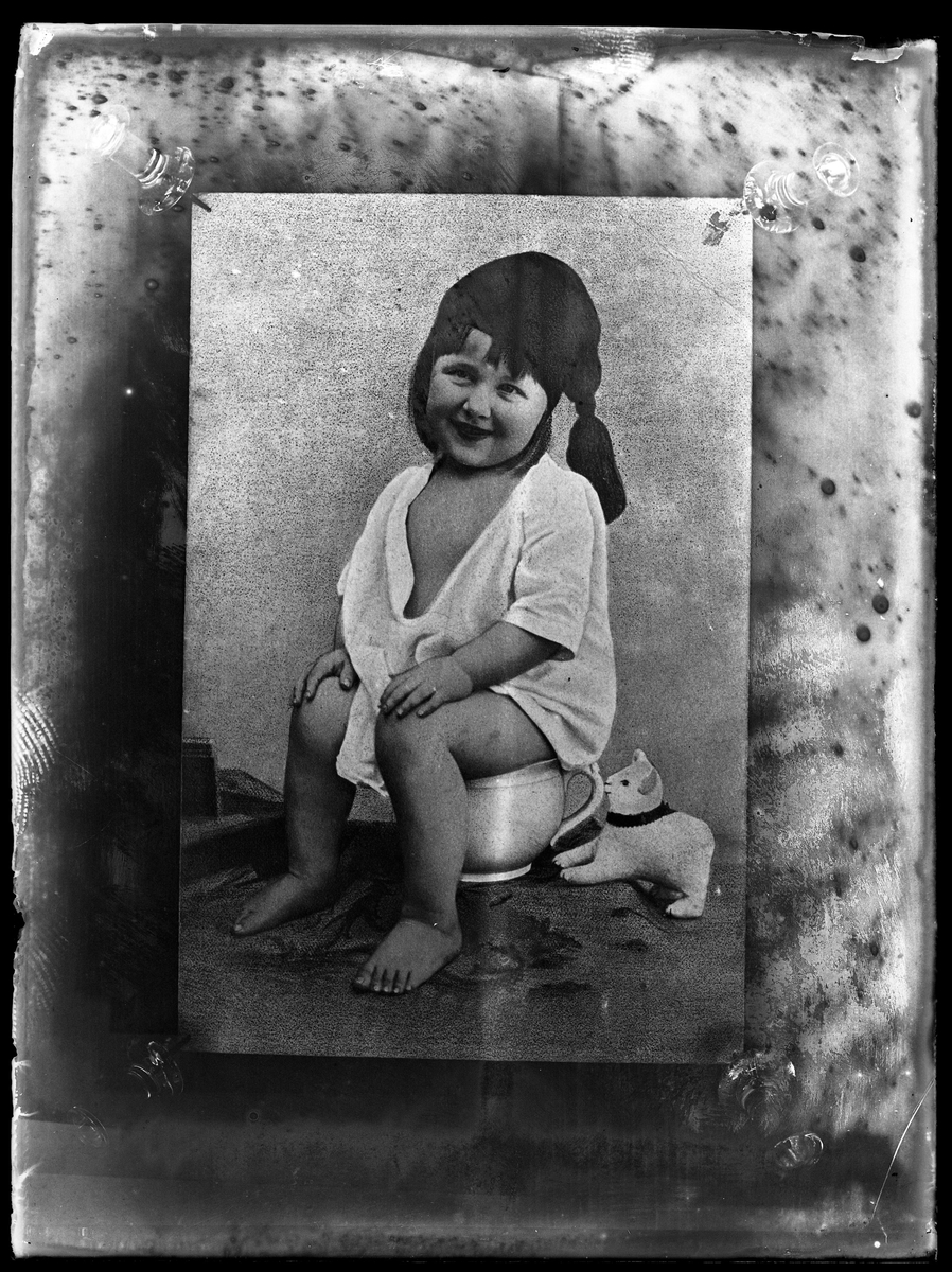 Reprofotografi av gosse i nattskjorta och -mössa sittandes på potta.