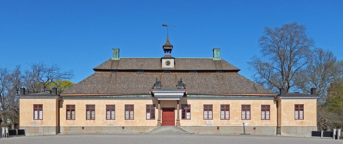 Huvudbyggnaden på Skogaholms herrgård är timrad i en våning med reveterade fasader. Grundplanen är den sex-delade planlösningen som modifierats genom extra sidokammare, en från fasaden framskjutande sal med förhöjt tak samt hörnpaviljonger på var gavel. En kolonnburen baldakin är placerad över ingången. Byggnaden har säteritak klätt med spån, de två hörnpaviljongernas tak är valmade och klädda med plåt. Byggnaden har två skorstenar klädda med kopparplåt. Centralt placerat i det översta takfallet, mitt för ingången, sitter  ett klocktorn med klocka, spåntak och vindflöjel. 

Byggnaden flyttades till Skansen 1930 från Skogaholms herrgård, Svennevads socken, Närke.