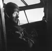 Flygförare Gunnar Rissler sitter i förarplatsen på flygplan Junkers F-13 under flygning. Vid F 19, Svenska frivilligkåren i Finland. En mekaniker står och vevar på vingen på flygplanet.