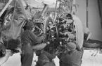 Motorbyte på flygplan Gloster Gladiator vid F 19, Svenska frivilligkåren i Finland. Tre mekaniker i arbete.