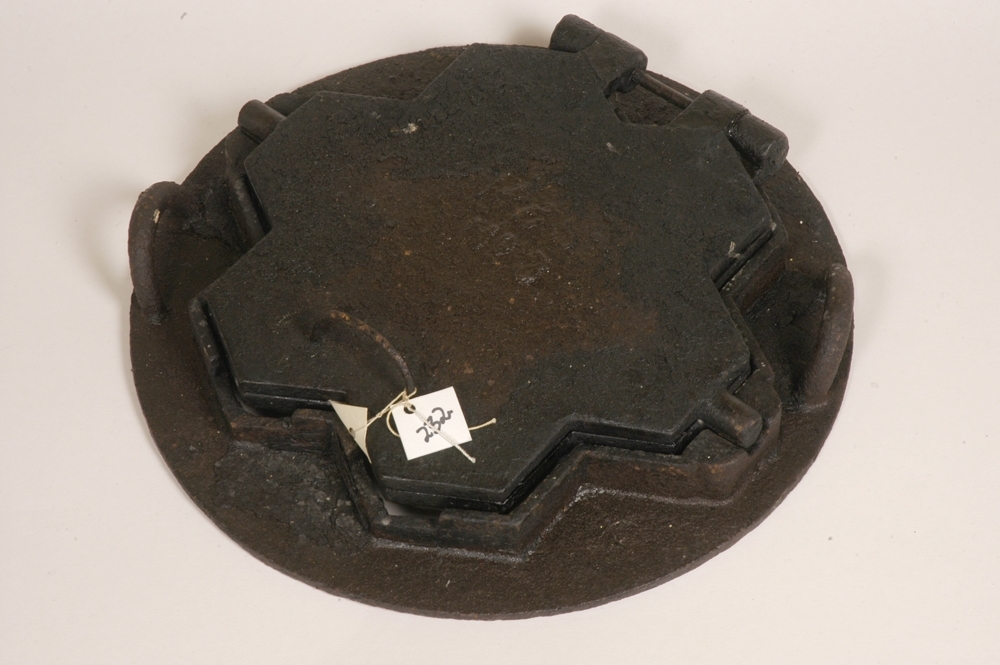 Relieffstøpt figur som inneholder G, V, krone og grener og stjernedekor.