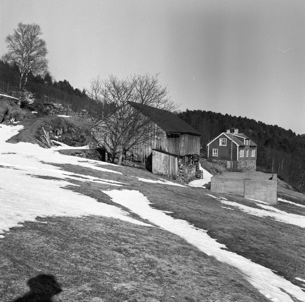 Prospektfotogafi av et gammelt gårdstun på Eikremshjellen med stove, fjøs og grunnmurene etter en revet bygning.