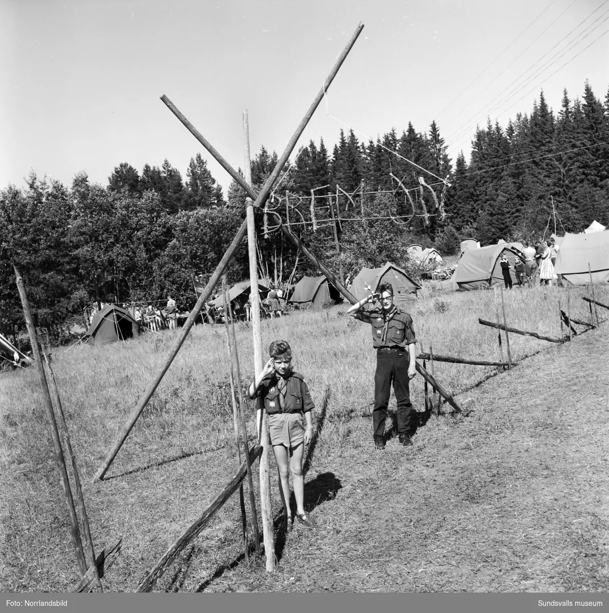 I juli 1959 anordnade Svenska Scoutförbundet sitt stora internationella läger på Rödön utanför Alnö. På första bilden ses lägerledaren Tage Allegård anlända med en grupp pojkscouter för några intensiva veckor på ön. Lägret hade förberetts under ett helt år och dagarna innan hade 70 pojkscouter och ledare hjälpts åt att bygga upp de olika lägerbyarna, som fick namn efter olika fyrar.  SCA hade upplåtit en pråm som låg för ankar i hamnen fylld med de matvaror som krävdes för att mätta de cirka 800 deltagarna.