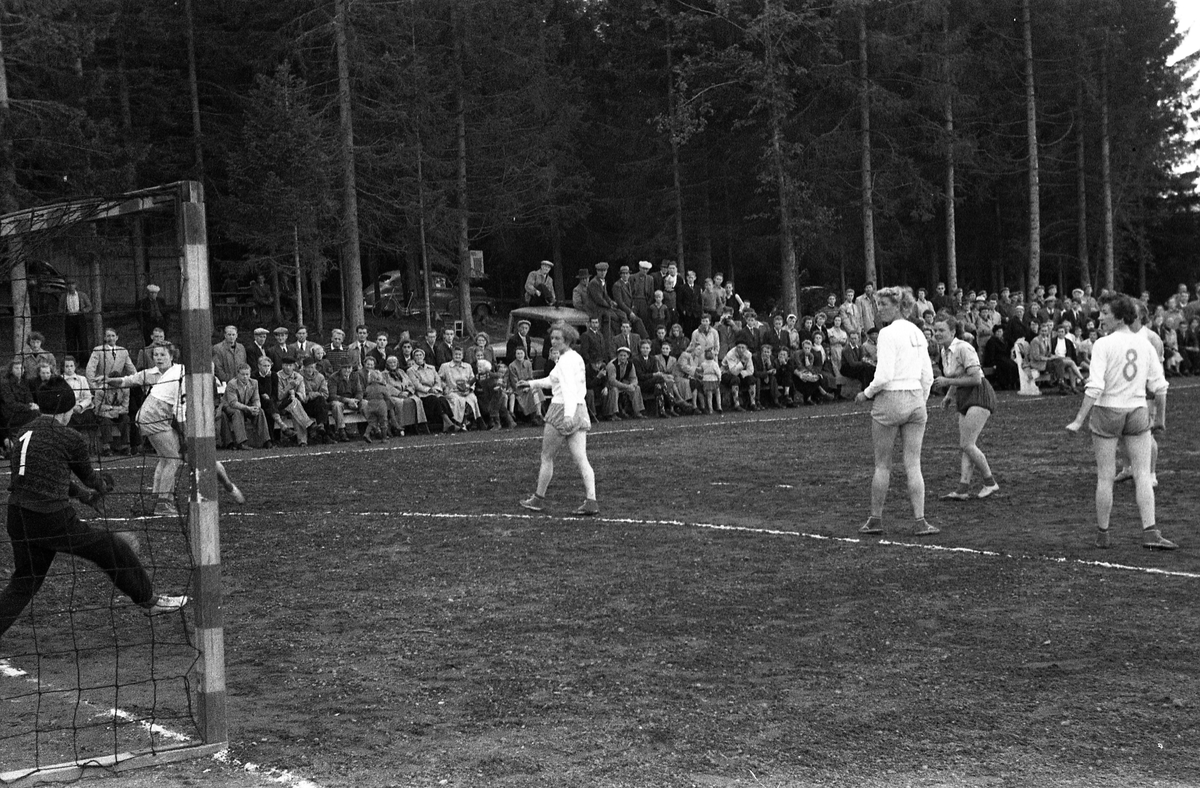 Håndballkamp på Kraby Idrettsplass september 1953. Kampen var kvartfinale i damenes Norgesmesterskap mot Nornen fra Bergen, en kamp Kraby vant og dermed kvlifiserte seg for semifinale. Krabys spillere, i de mørkeste buksene, er identifisert, men for navn henvises til lagbilde TMF-06483.
14 bilder som viser kampsituasjoner og publikum.