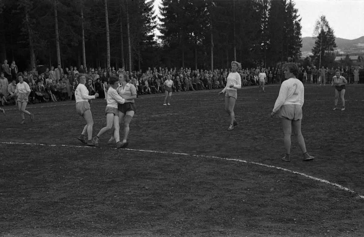 Håndballkamp på Kraby Idrettsplass september 1953. Kampen var kvartfinale i damenes Norgesmesterskap mot Nornen fra Bergen, en kamp Kraby vant og dermed kvlifiserte seg for semifinale. Krabys spillere, i de mørkeste buksene, er identifisert, men for navn henvises til lagbilde TMF-06483.
14 bilder som viser kampsituasjoner og publikum.