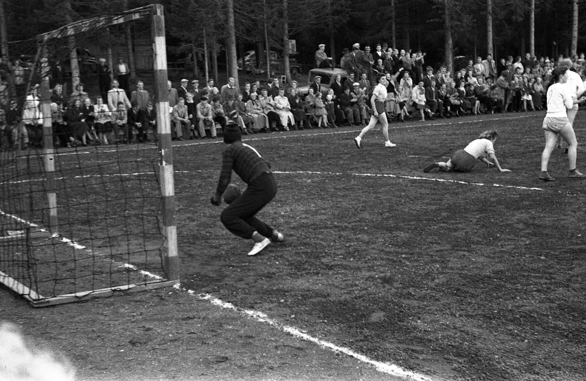 Håndballkamp på Kraby Idrettsplass september 1953. Kampen var kvartfinale i damenes Norgesmesterskap mot Nornen fra Bergen, en kamp Kraby vant og dermed kvlifiserte seg for semifinale. Krabys spillere, i de mørkeste buksene, er identifisert, men for navn henvises til lagbilde TMF-06483.
14 bilder som viser kampsituasjoner og publikum.
