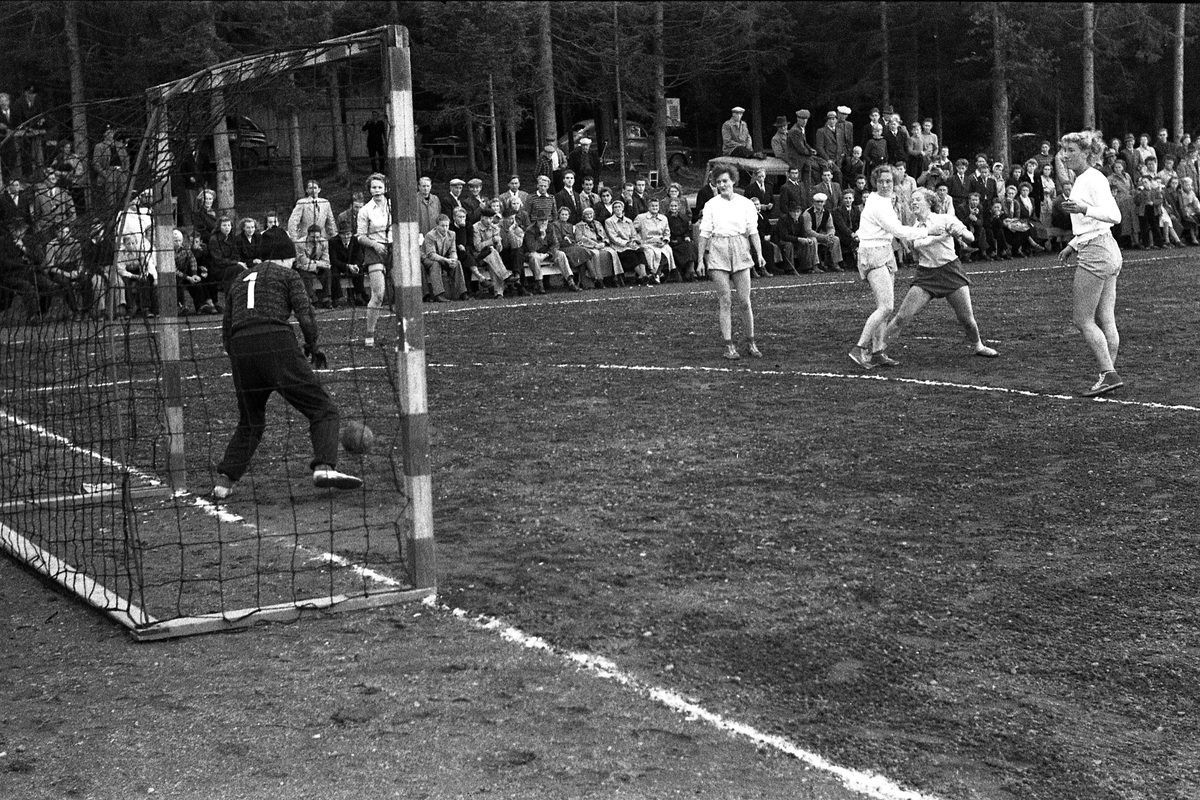 Håndballkamp på Kraby Idrettsplass september 1953. Kampen var kvartfinale i damenes Norgesmesterskap mot Nornen fra Bergen, en kamp Kraby vant og dermed kvlifiserte seg for semifinale. Krabys spillere, i de mørkeste buksene, er identifisert, men for navn henvises til lagbilde TMF-06483.
14 bilder som viser kampsituasjoner og publikum.