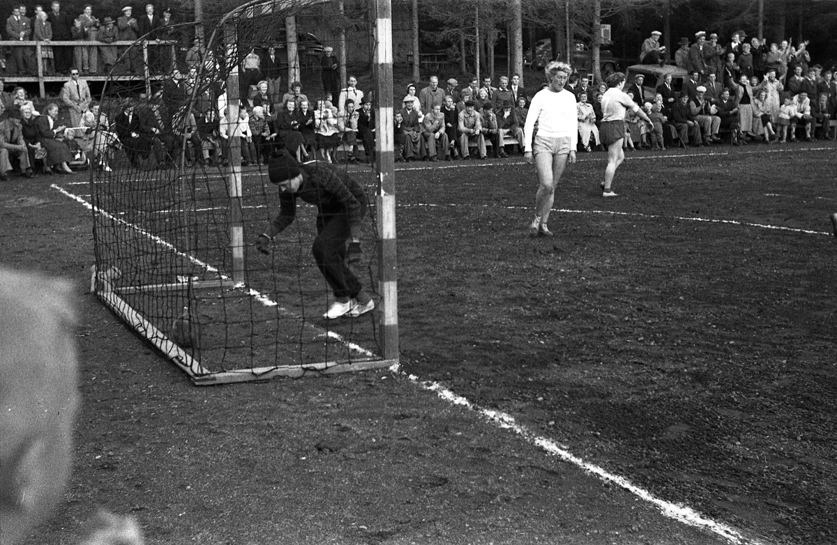Håndballkamp på Kraby Idrettsplass september 1953. Kampen var kvartfinale i damenes Norgesmesterskap mot Nornen fra Bergen, en kamp Kraby vant og dermed kvlifiserte seg for semifinale. Krabys spillere, i de mørkeste buksene, er identifisert, men for navn henvises til lagbilde TMF-06483.
14 bilder som viser kampsituasjoner og publikum.