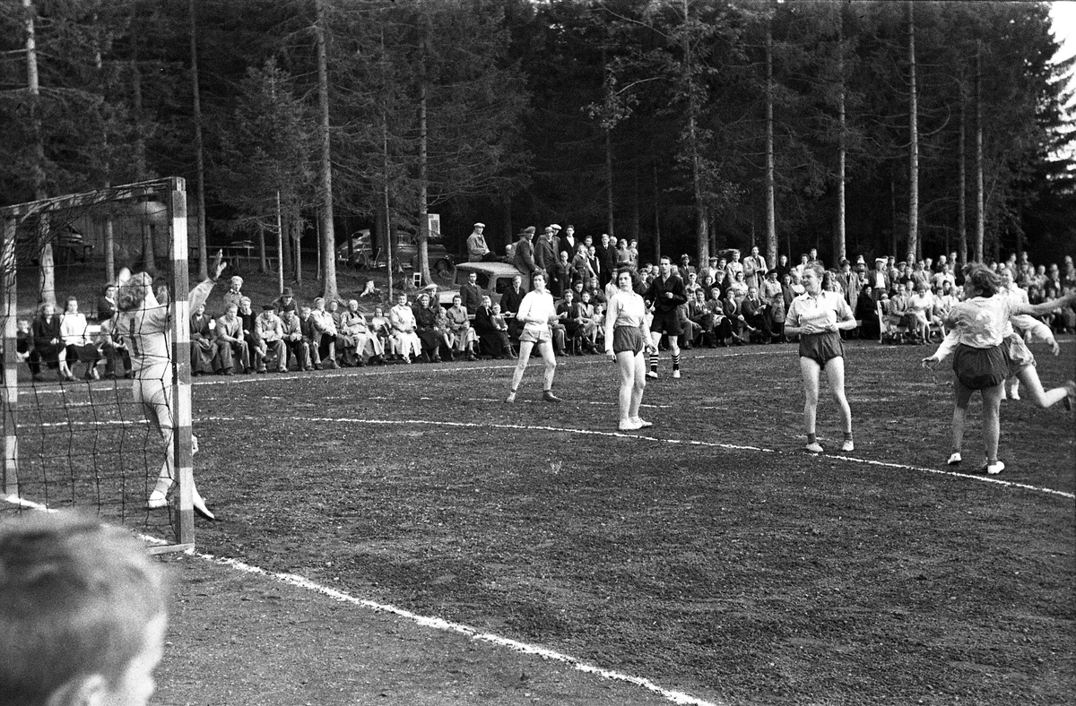 Håndballkamp på Kraby Idrettsplass september 1953. Kampen var kvartfinale i damenes Norgesmesterskap mot Nornen fra Bergen, en kamp Kraby vant og dermed kvlifiserte seg for semifinale. Krabys spillere, i de mørkeste buksene, er identifisert, men for navn henvises til lagbilde TMF-06483.
14 bilder som viser kampsituasjoner og publikum.